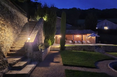 Miniature Location salle Beaujeu (Rhône) - Le Domaine de Vavril #31 Salle voûtée en pierre avec un sol en béton poli, éclairée par des lumières chaudes, et un vase de fleurs au centre.
