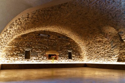 Miniature Location salle Beaujeu (Rhône) - Le Domaine de Vavril #41 Salle voûtée en pierre avec un sol en béton poli, éclairée par des lumières chaudes, et un vase de fleurs au centre.