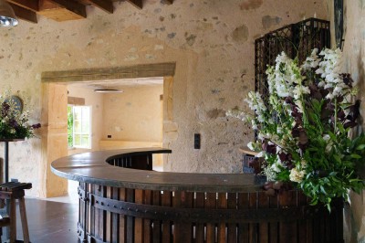 Miniature Location salle Beaujeu (Rhône) - Le Domaine de Vavril #39 Salle voûtée en pierre avec un sol en béton poli, éclairée par des lumières chaudes, et un vase de fleurs au centre.