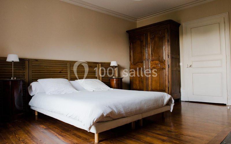 Chambre avec un lit double, deux tables de chevet avec lampes, une armoire en bois et un sol en parquet.