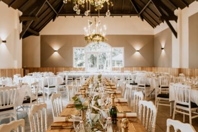 Salle de réception décorée avec des tables rondes dressées, des fleurs colorées et un mur de briques apparentes.