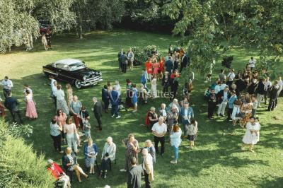 Salle de réception décorée avec des tables rondes dressées, des fleurs colorées et un mur de briques apparentes.