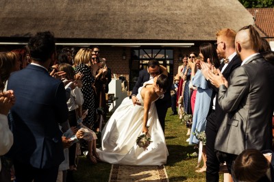 Salle de réception décorée avec des tables rondes dressées, des fleurs colorées et un mur de briques apparentes.