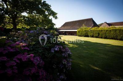 Salle de réception décorée avec des tables rondes dressées, des fleurs colorées et un mur de briques apparentes.