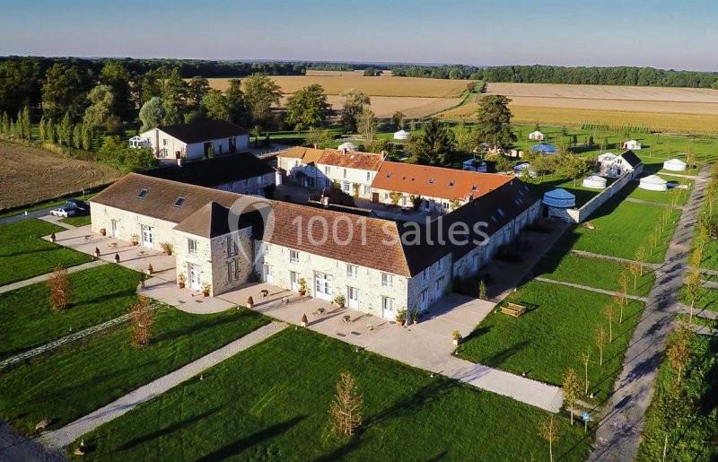 Vue aérienne d'un domaine rural avec bâtiments en pierre, toits en tuiles et espaces verts environnants.