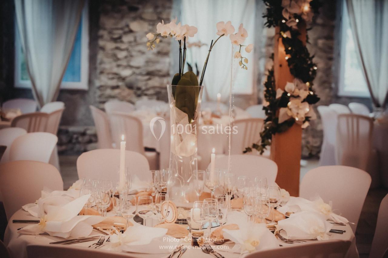 Table de réception élégamment décorée avec des orchidées blanches, des bougies et de la vaisselle raffinée.