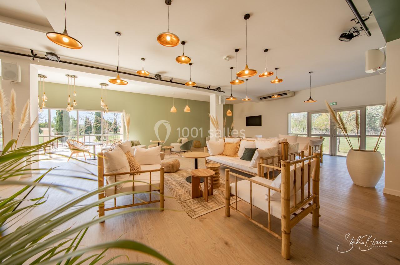 Salle lumineuse avec mobilier en bois et décoration naturelle, grandes fenêtres donnant sur un espace extérieur verdoyant.