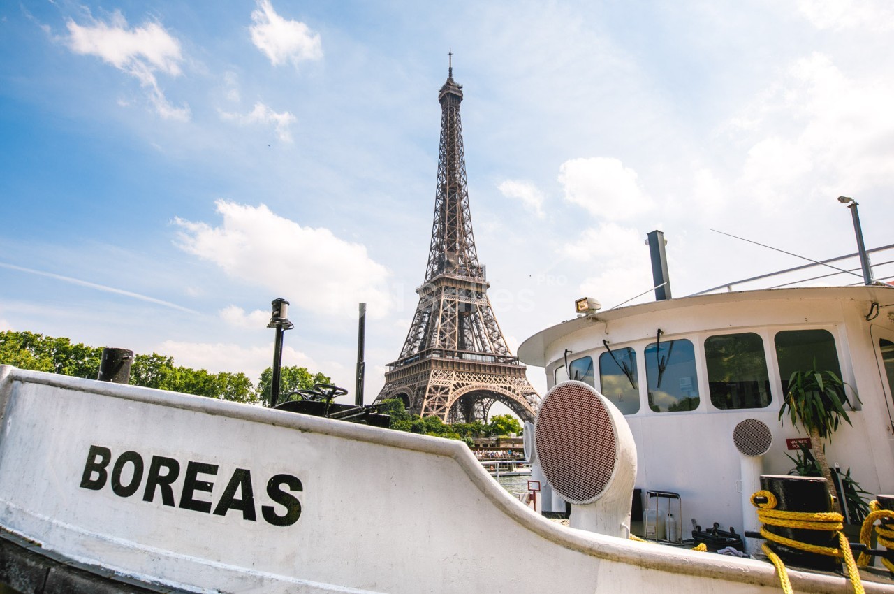Vue de la tour Eiffel depuis les quais de la Seine, avec un bateau nommé ’Boreas’ au premier plan.