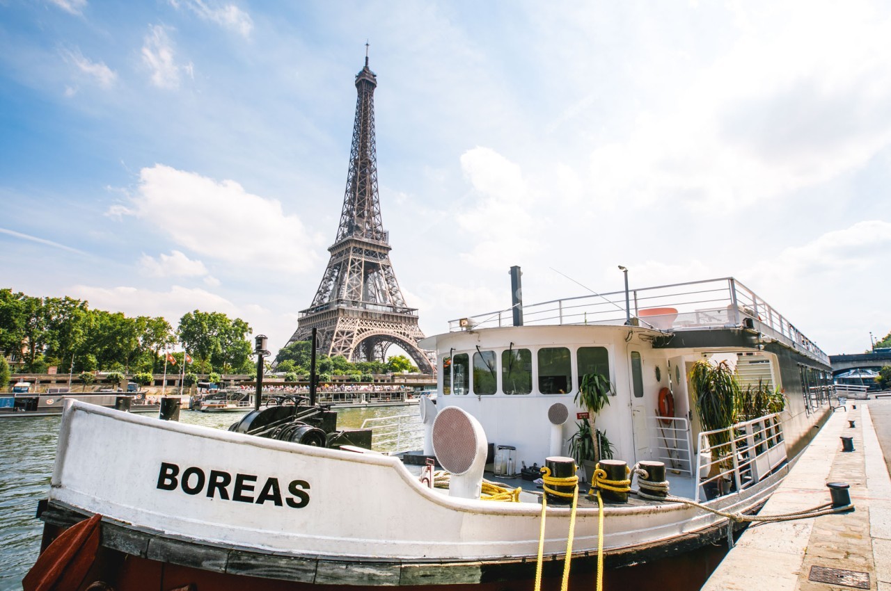 Péniche amarrée sur la Seine avec la tour Eiffel en arrière-plan par une journée ensoleillée.