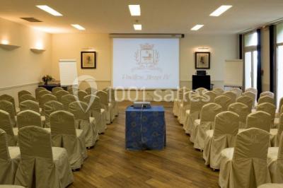 Deux tables de massage recouvertes de draps beiges, avec une vue sur un paysage urbain et verdoyant à travers une fenêtre.