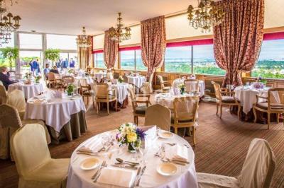 Deux tables de massage recouvertes de draps beiges, avec une vue sur un paysage urbain et verdoyant à travers une fenêtre.