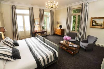 Deux tables de massage recouvertes de draps beiges, avec une vue sur un paysage urbain et verdoyant à travers une fenêtre.