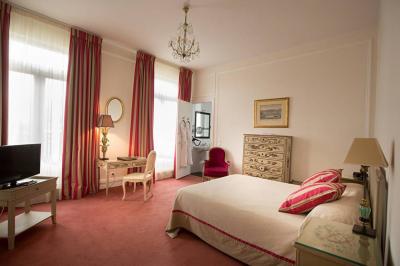 Deux tables de massage recouvertes de draps beiges, avec une vue sur un paysage urbain et verdoyant à travers une fenêtre.