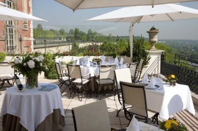 Deux tables de massage recouvertes de draps beiges, avec une vue sur un paysage urbain et verdoyant à travers une fenêtre.