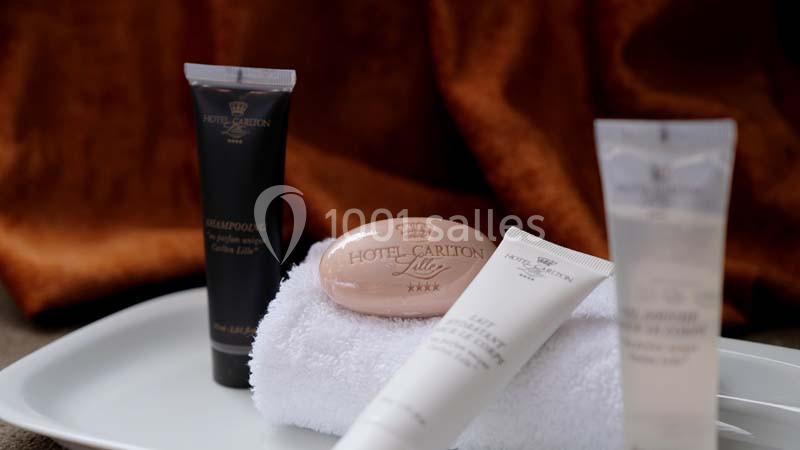 Produits de toilette d'hôtel disposés sur une serviette blanche, comprenant savon, shampooing et lotions.