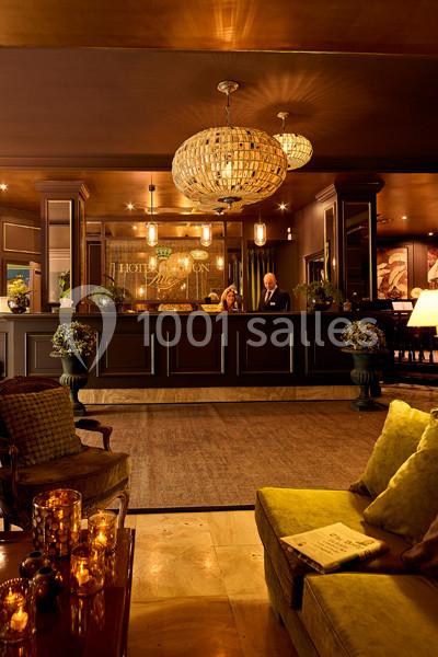 Réception d'un hôtel élégant avec un comptoir en bois sombre, lustres lumineux et décoration chaleureuse.