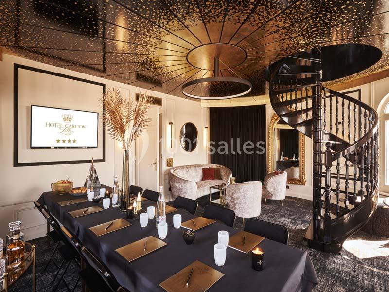 Salle de réunion élégante avec table dressée, fauteuils luxueux, escalier en colimaçon et décorations dorées.