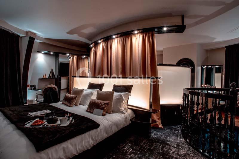 Chambre élégante avec lit double, coussins décoratifs, éclairage tamisé et plateau-repas sur la literie.