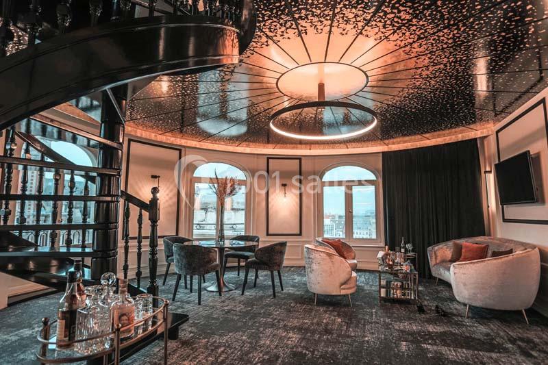 Salon élégant avec escalier en colimaçon, mobilier moderne, plafond décoratif et vue sur l'extérieur par de grandes fenêtres.