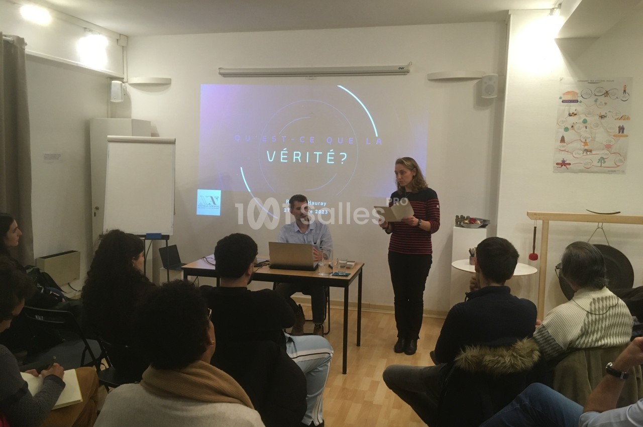 Un groupe de personnes assiste à une présentation sur le thème de la vérité dans une salle de réunion.