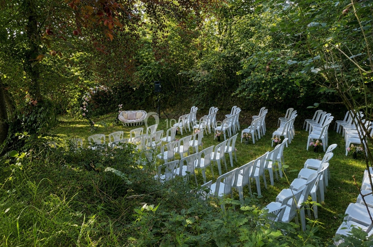 Chaises blanches disposées en rangées dans un jardin verdoyant pour une cérémonie en plein air.