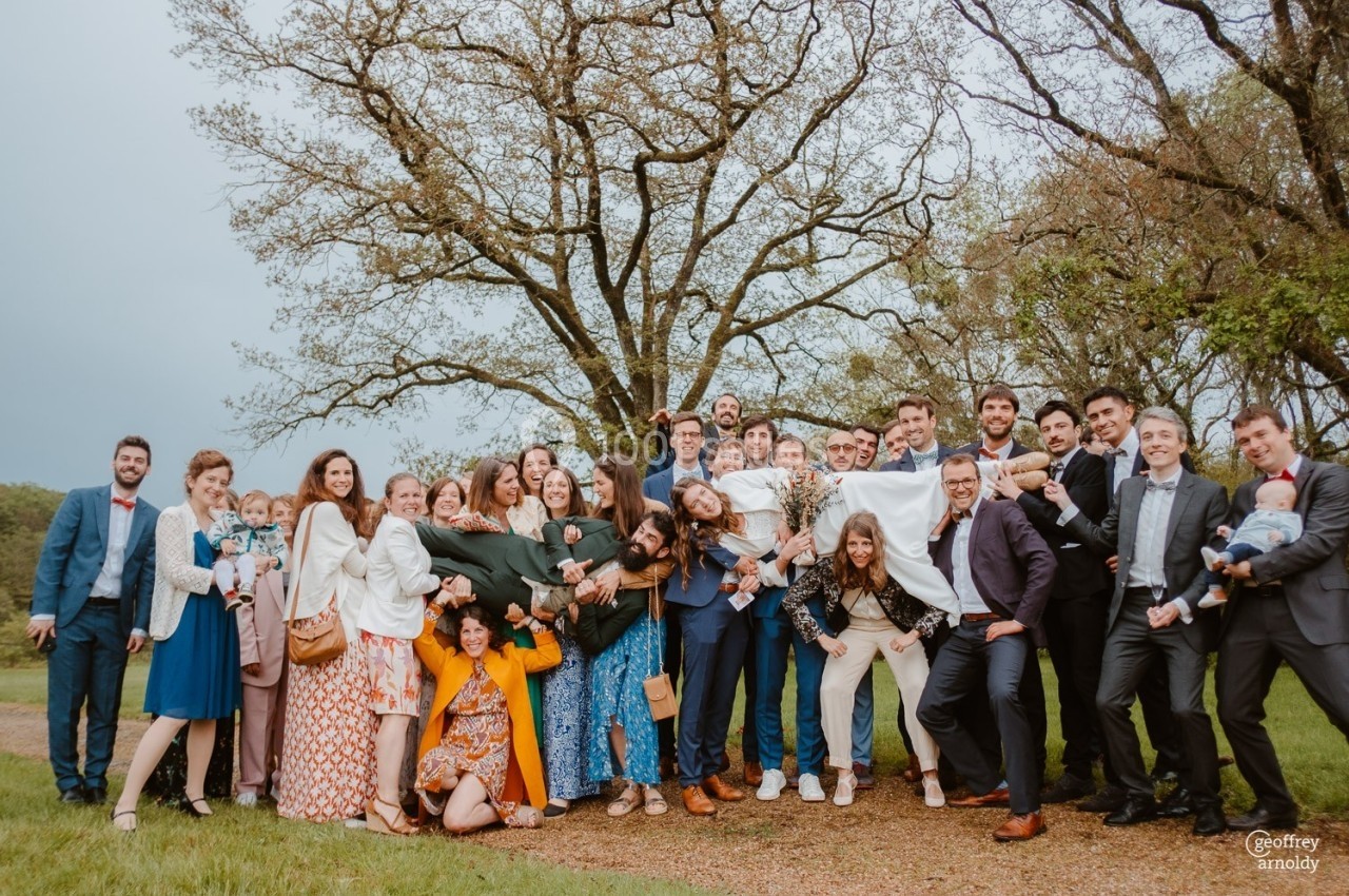 Un grand groupe de personnes posant joyeusement devant des arbres dans un cadre extérieur.