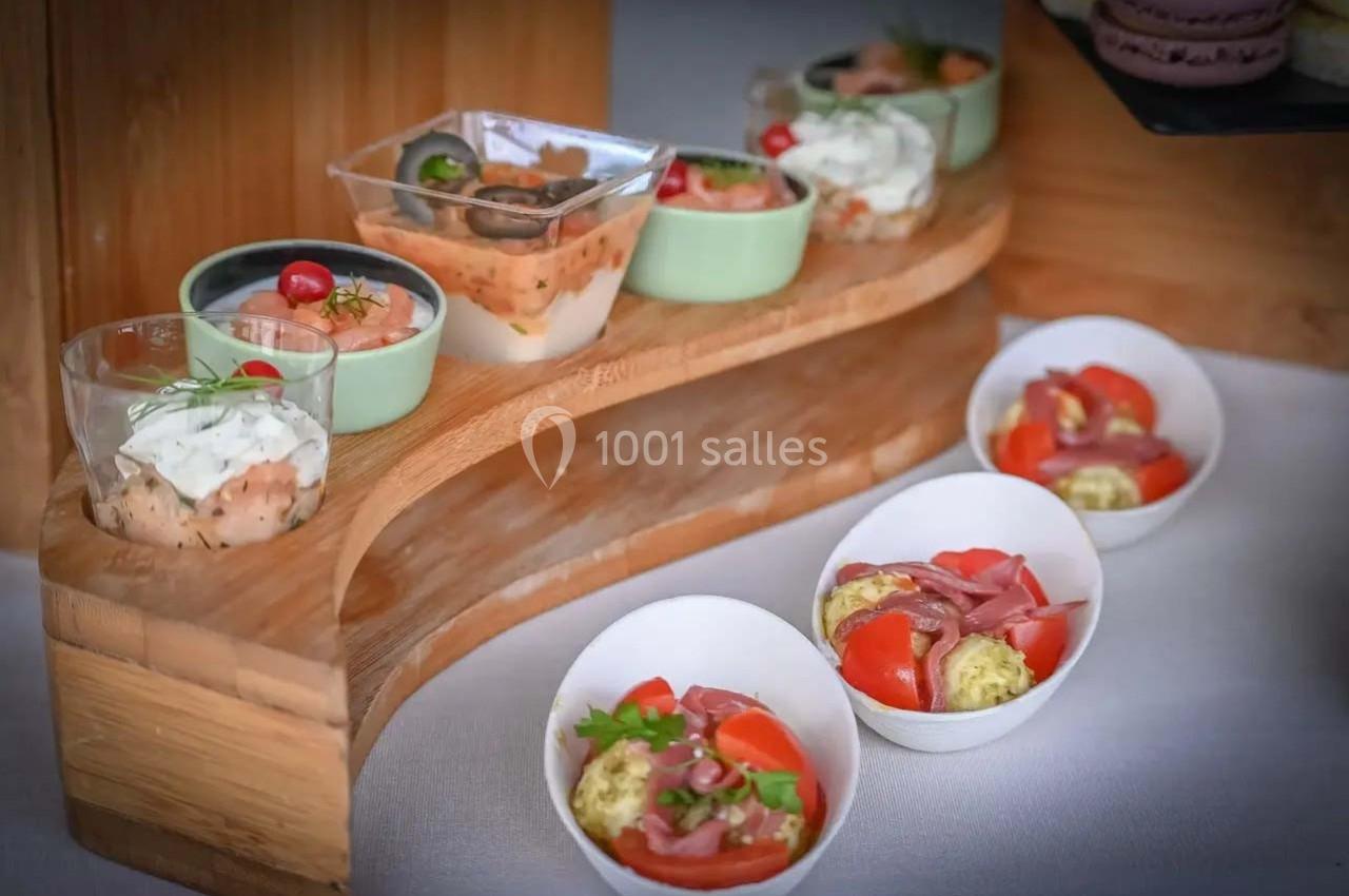 Assortiment de verrines et bols contenant des entrées variées, disposés sur un présentoir en bois.