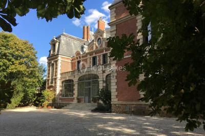 Façade d'un château éclairé au crépuscule, vue depuis un parterre de fleurs au premier plan.