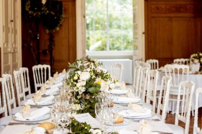 Façade d'un château éclairé au crépuscule, vue depuis un parterre de fleurs au premier plan.