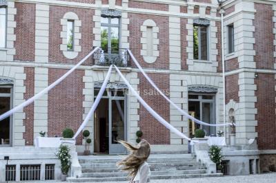 Façade d'un château éclairé au crépuscule, vue depuis un parterre de fleurs au premier plan.