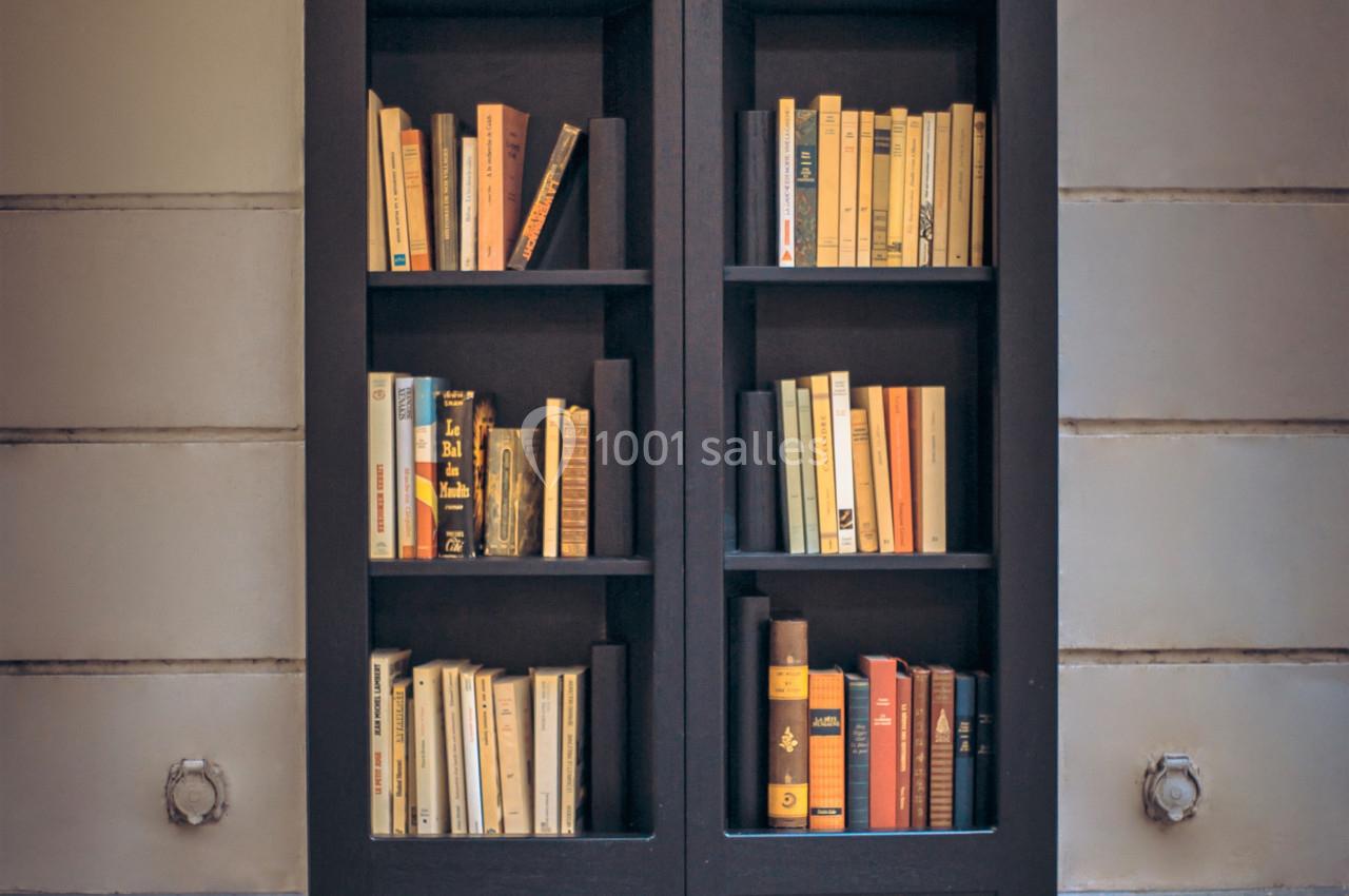 Bibliothèque intégrée dans une façade, remplie de livres aux couvertures variées, dans un cadre urbain.