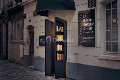 Bibliothèque intégrée dans une façade, remplie de livres aux couvertures variées, dans un cadre urbain.