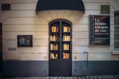 Bibliothèque intégrée dans une façade, remplie de livres aux couvertures variées, dans un cadre urbain.