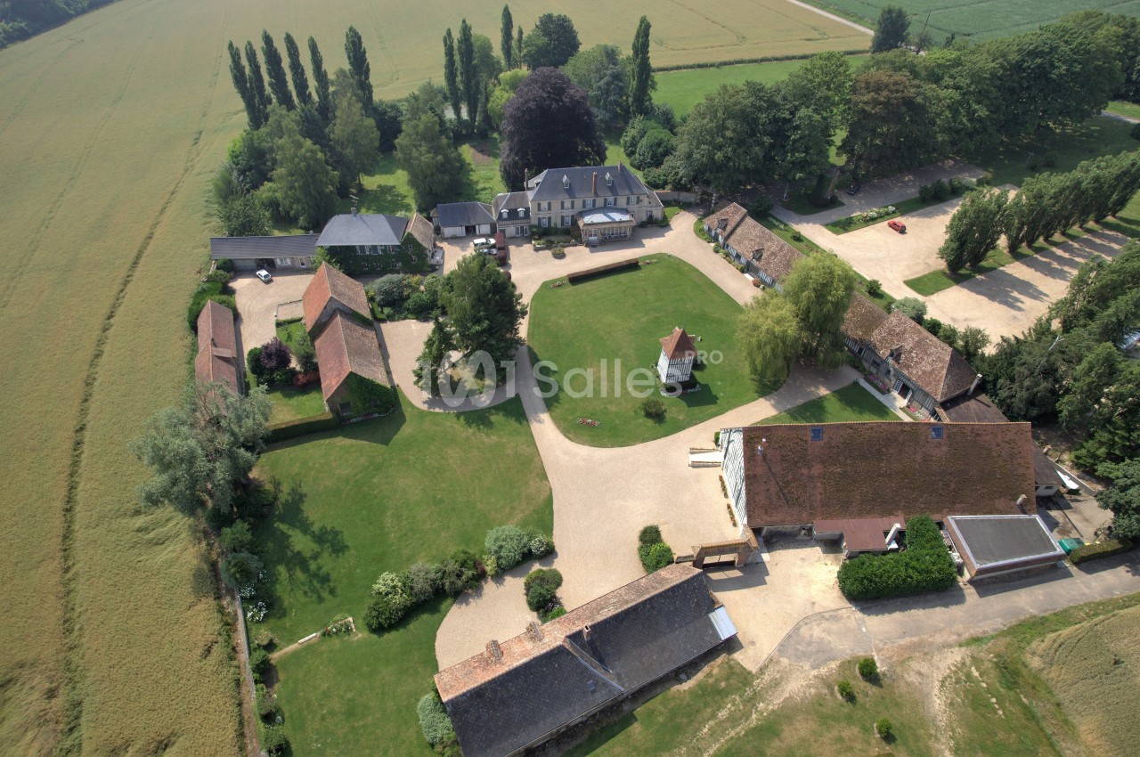 Vue aérienne d'un domaine rural avec bâtiments en pierre, cours, pelouses et champs environnants.