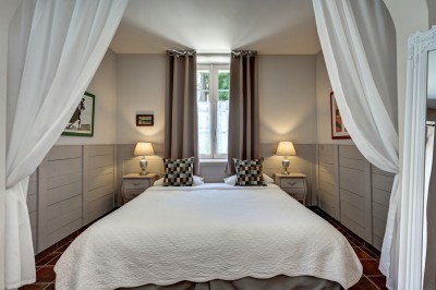 Salle en pierre avec une grande cheminée, table ronde dressée avec chaises rembourrées et bouteilles d'eau.