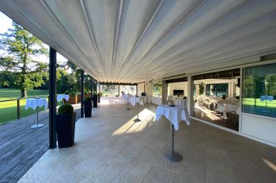 Salle de réception décorée pour un mariage, avec des tables rondes dressées, nappes blanches et arrangements floraux.