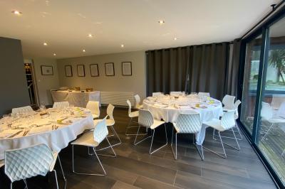 Salle de réception décorée pour un mariage, avec des tables rondes dressées, nappes blanches et arrangements floraux.