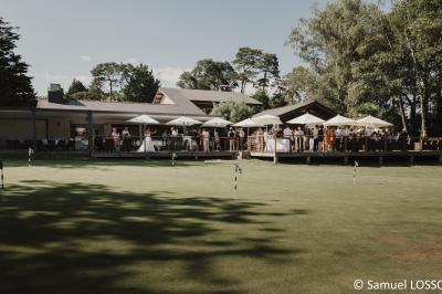 Salle de réception décorée pour un mariage, avec des tables rondes dressées, nappes blanches et arrangements floraux.