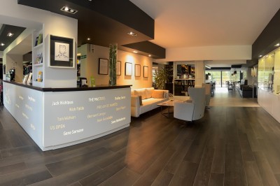 Salle de réception décorée pour un mariage, avec des tables rondes dressées, nappes blanches et arrangements floraux.
