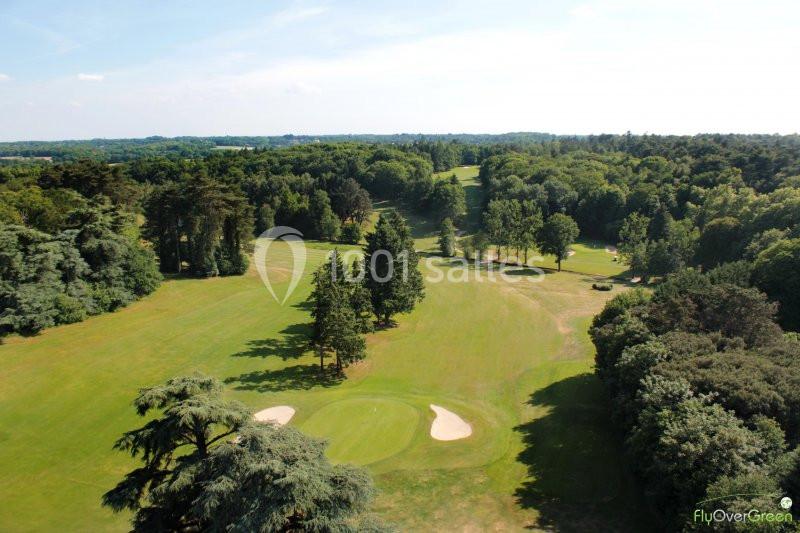 Vue aérienne d'un terrain de golf entouré de forêts, avec des bunkers et des allées verdoyantes.
