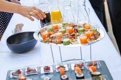 Salle lumineuse avec baies vitrées, tables rondes dressées avec nappes blanches et chaises modernes.