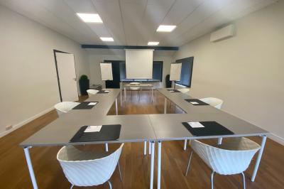 Salle lumineuse avec baies vitrées, tables rondes dressées avec nappes blanches et chaises modernes.