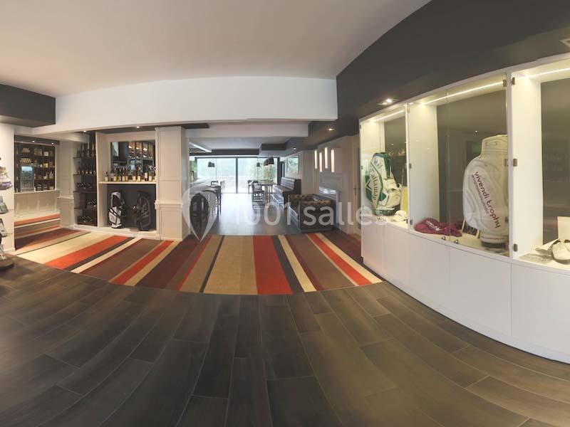 Vue intérieure d'un espace moderne avec vitrines exposant des objets, un bar et des tables en arrière-plan.