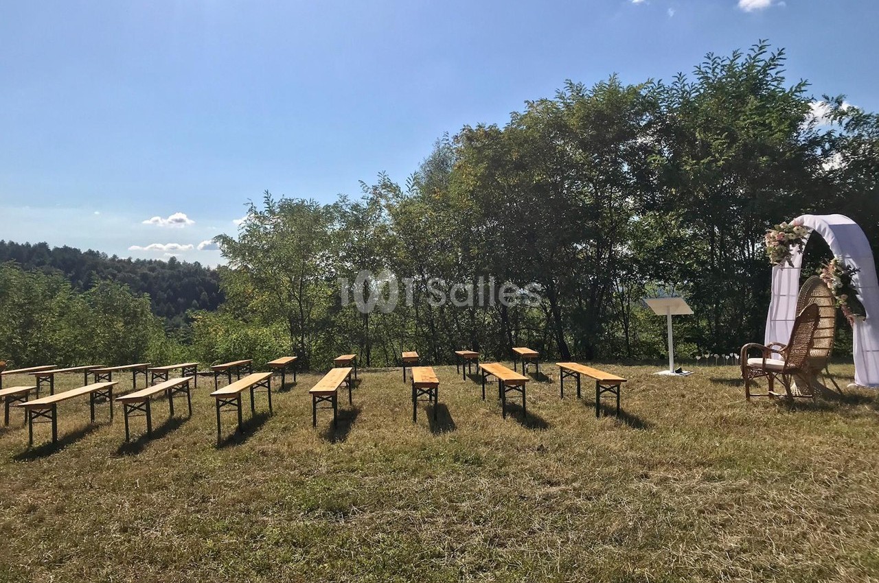 Chaises et bancs disposés en extérieur sur une pelouse, face à une arche décorée pour une cérémonie en plein air.