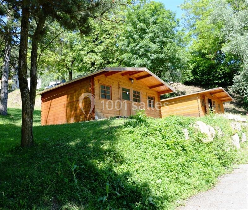 Deux chalets en bois sur une colline verdoyante entourée d'arbres en plein été.