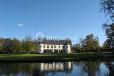 Une femme en robe de mariée défile sur un tapis rouge devant un public dans une salle éclairée par des lustres.