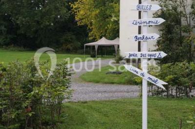 Une femme en robe de mariée défile sur un tapis rouge devant un public dans une salle éclairée par des lustres.