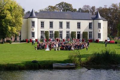 Une femme en robe de mariée défile sur un tapis rouge devant un public dans une salle éclairée par des lustres.
