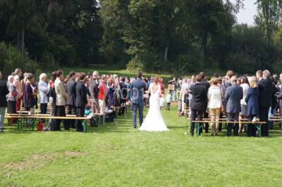 Une femme en robe de mariée défile sur un tapis rouge devant un public dans une salle éclairée par des lustres.