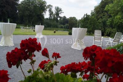 Une femme en robe de mariée défile sur un tapis rouge devant un public dans une salle éclairée par des lustres.
